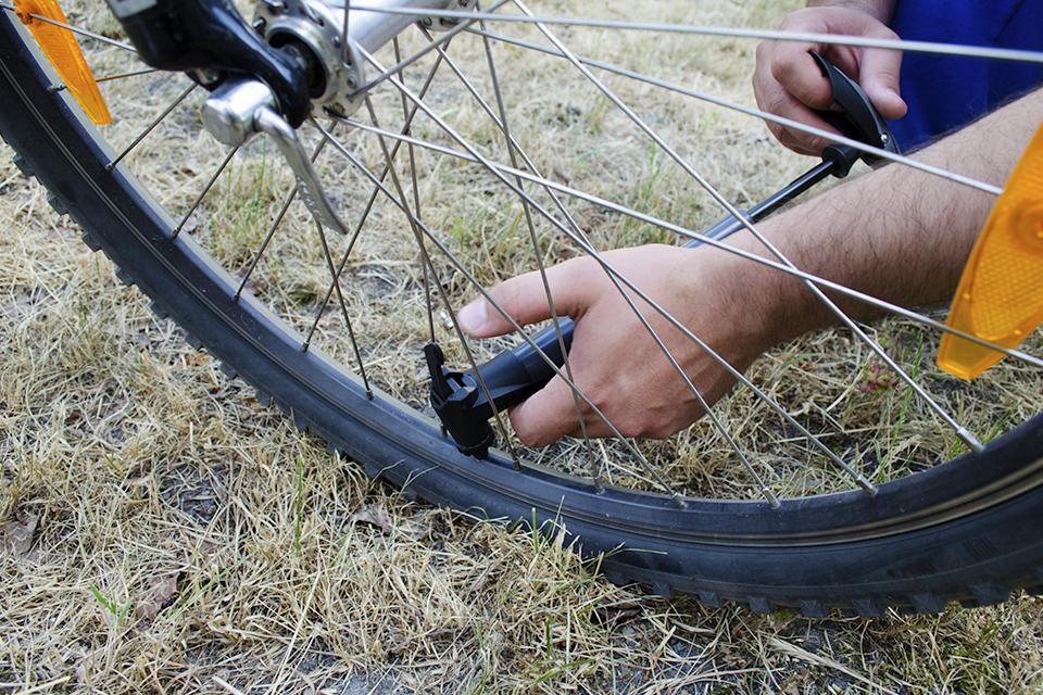 A person fixing the bike tyres with a pump.