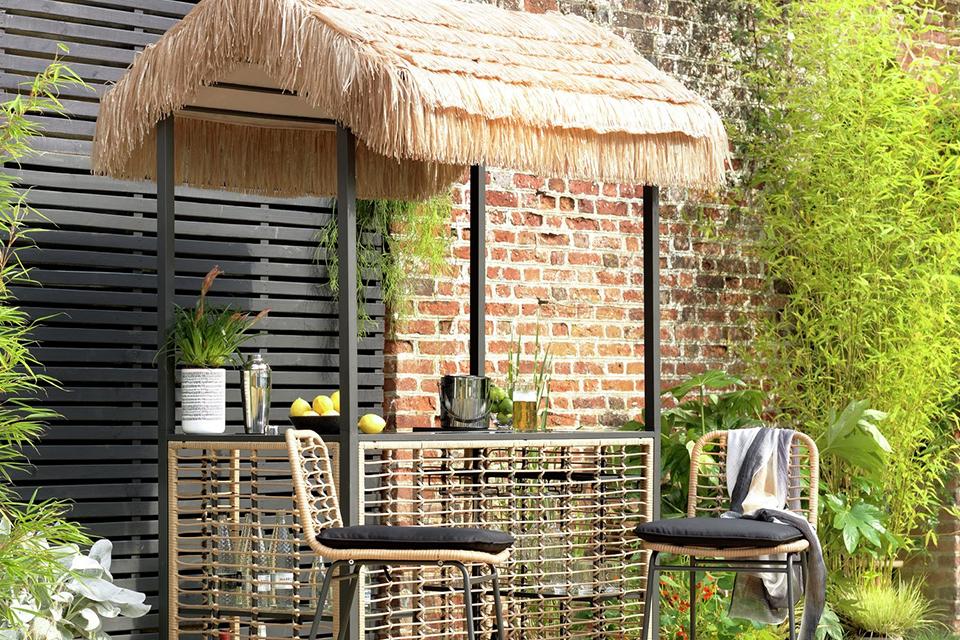 A Habitat beach bar gazebo with stools in natural finish placed in a garden.