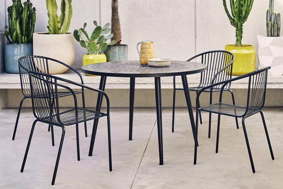 A black bistro set placed outdoor next to potted plants.