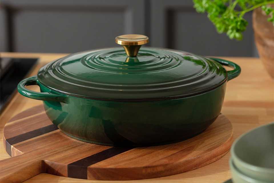 Green cast iron casserole dish on wooden chopping board.