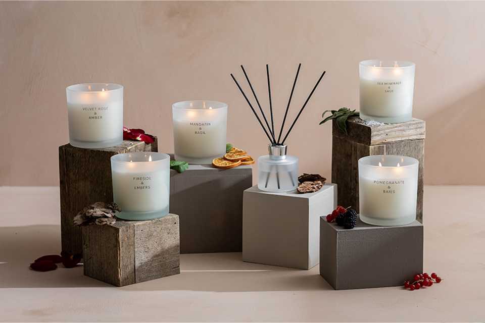 A selection of candles in glass jars on wooden plinths.