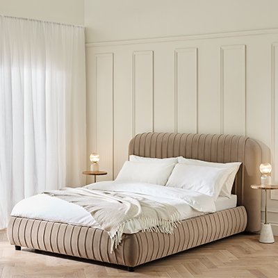 Cloud cream lined bedframe ith white bedding in large room painted white.
