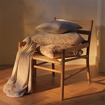 Cosy bed with fur cushions and throw in neutral colours.