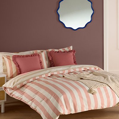 Pink bedroom with stripe pink bedding and curved bobble mirror.