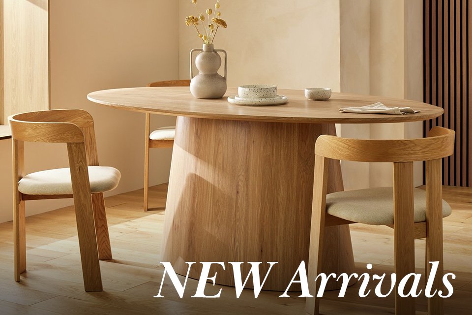 Wooden circle dining table with wooden mid century chairs with white seat cushions.