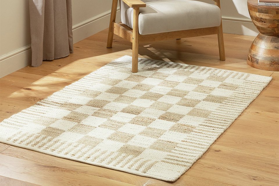 Beige checkerboard design rug in wool and jute on a wooden floor.