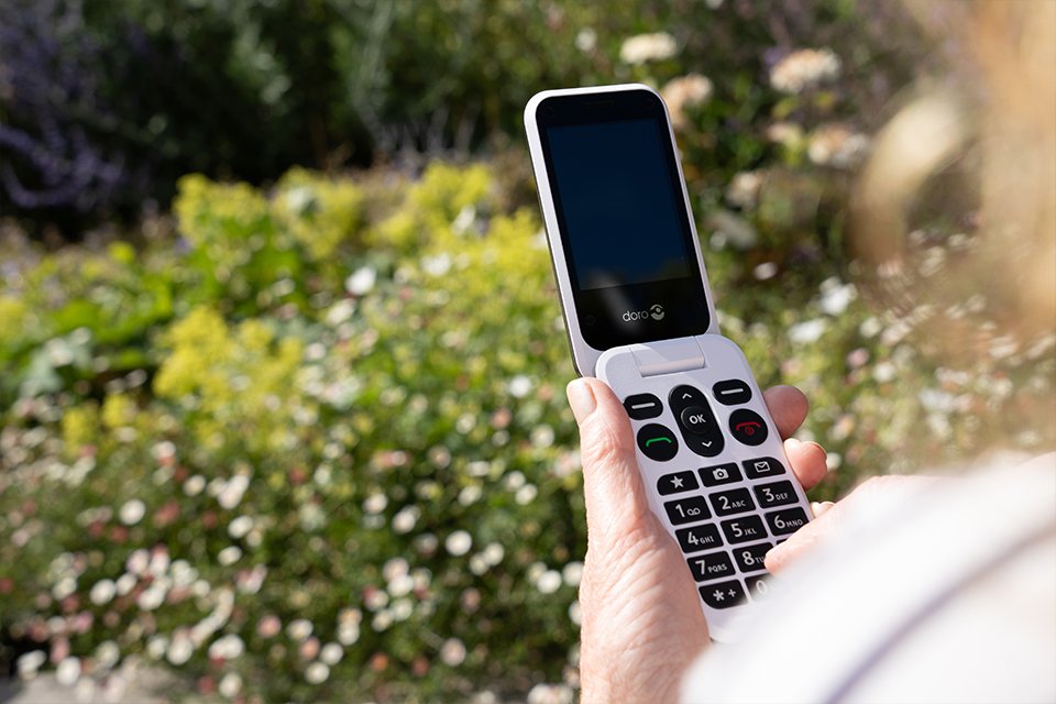 A hand holding an open Doro Leva L20 flip phone. 