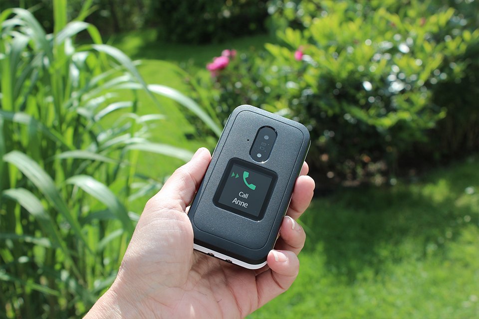 Doro Leva E30 clamshell feature phone in hand showing a call on the external screen. 