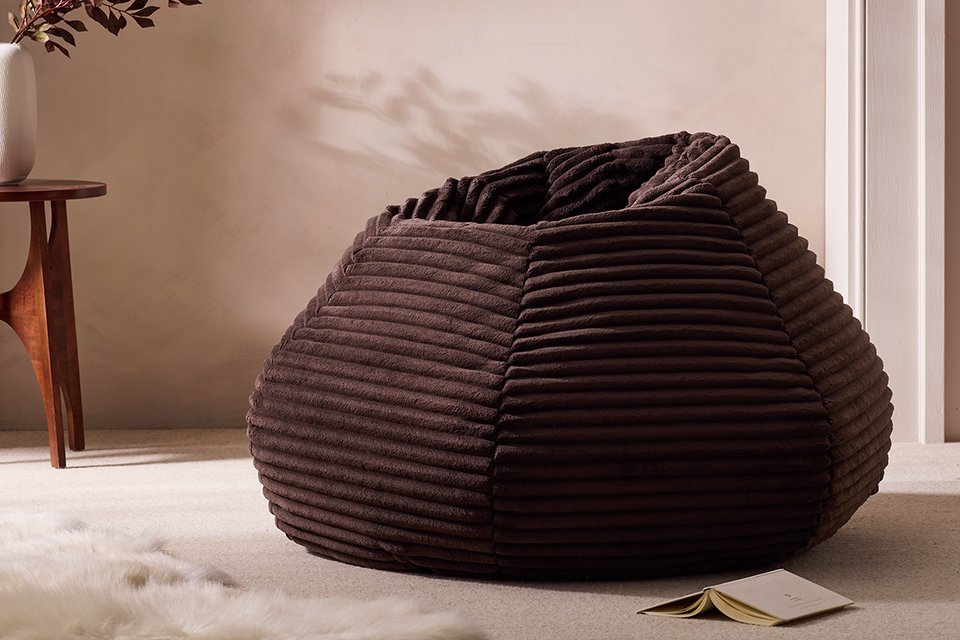 Brown bean bag in living room next to wooden side table.