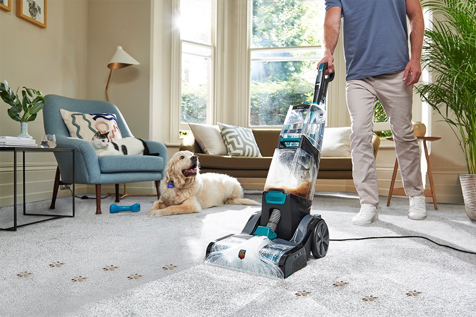 Person using carpet cleaner to clean their home. 