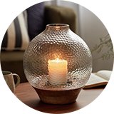 Glass hurricane candle vade on coffee table.