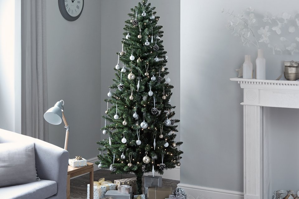 A Habitat 6ft slim evergreen tree with gifts under it in a living room.