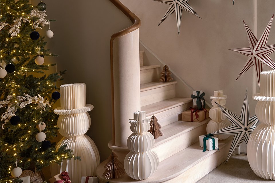 A living room decorated for Christmas with a tree, snowmen, a star and some gifts.