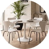 A white round dining table next to matching chairs.