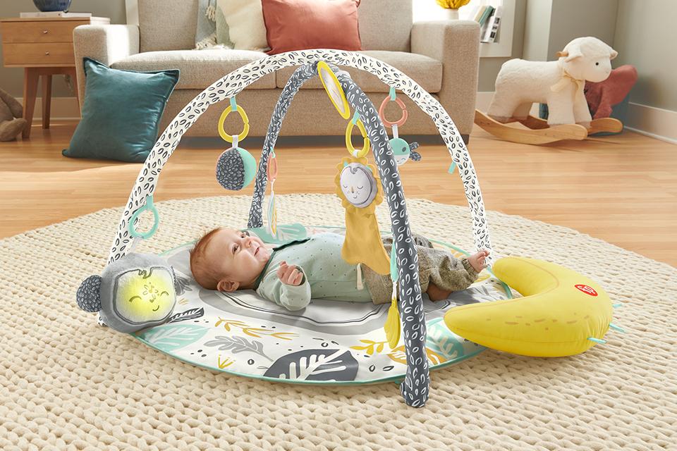 A smiling baby plays with a Fisher-Price monkey gym.