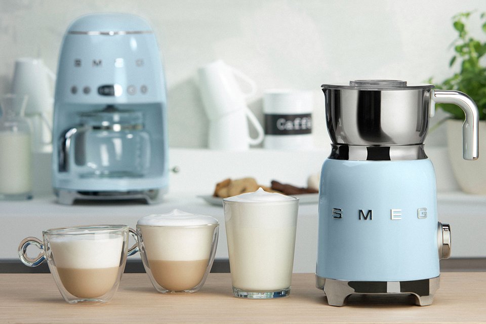 A Smeg 50's style retro milk frother near different coffees.