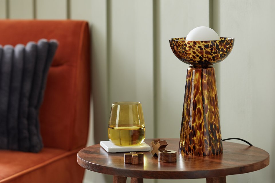 Living room side table with table lamp and glass.