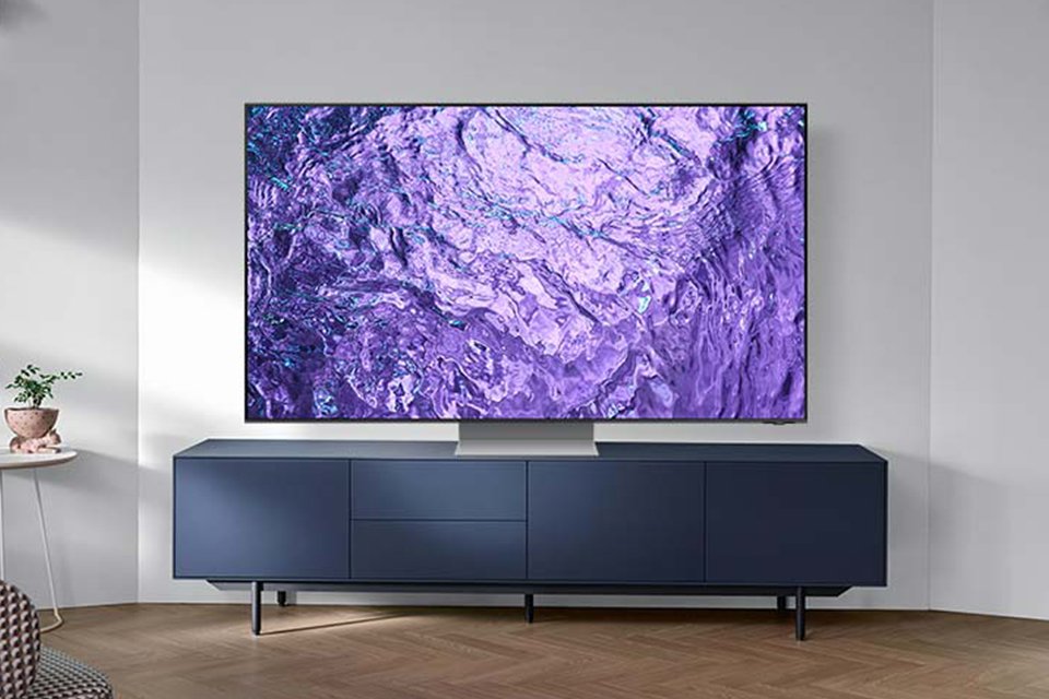 A Samsung QN700C 8K Neo QLED TV placed on a tv stand in a brightly lit living room.