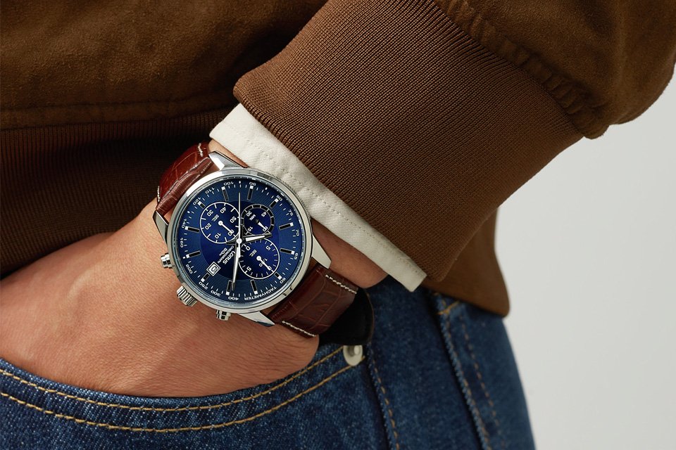 A man wearing a Lorus men's chronograph brown leather strap watch with a dark blue dial.