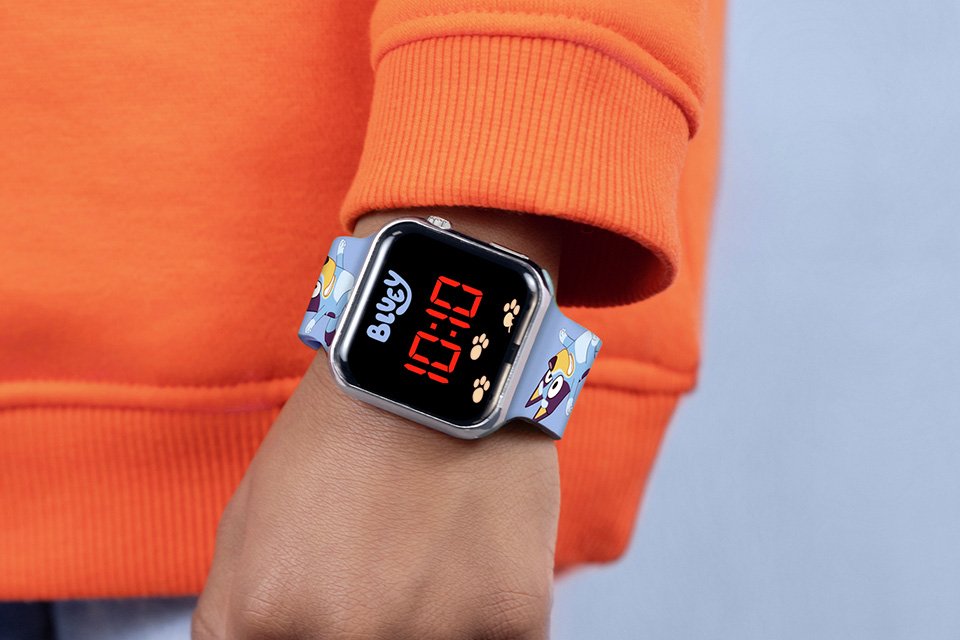 A young boy wearing a digital watch with a Bluey printed strap.