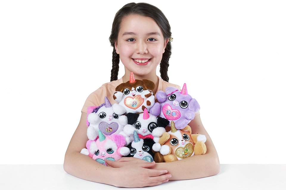 A child with an armful of ZURU Rainbocorns Sparkle Heart Surprise Series 3 Puppycorns.