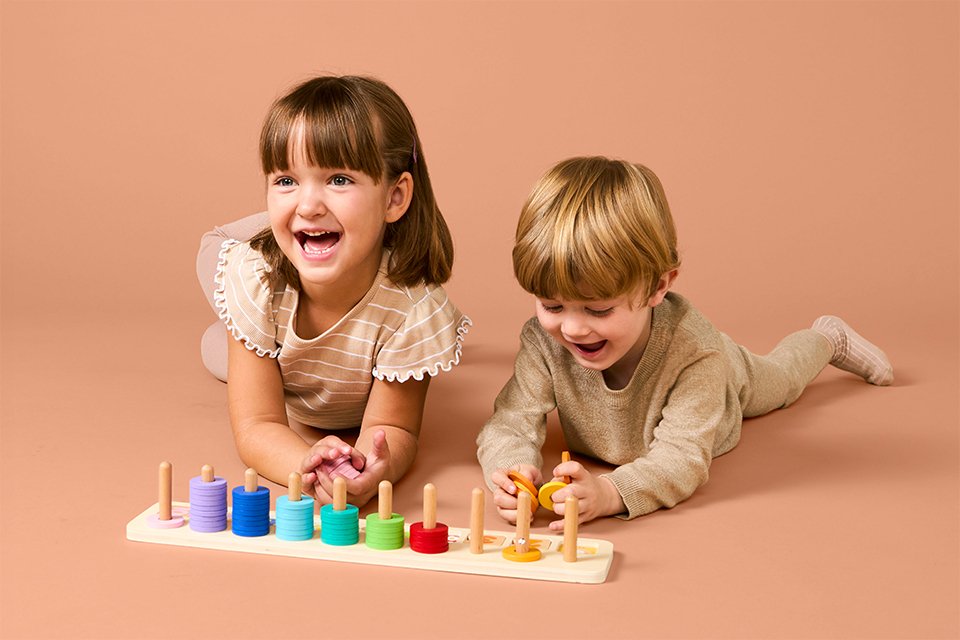Two toddlers smiling while playing with Chad Valley's educational toy.