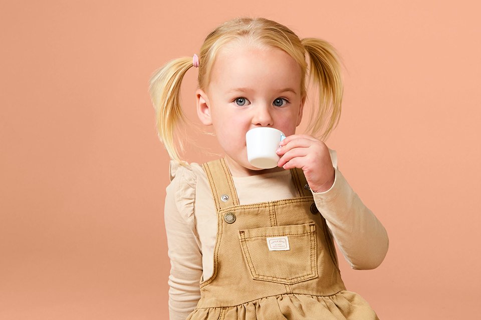 A young girl sipping from a Chad Valley toy cup.