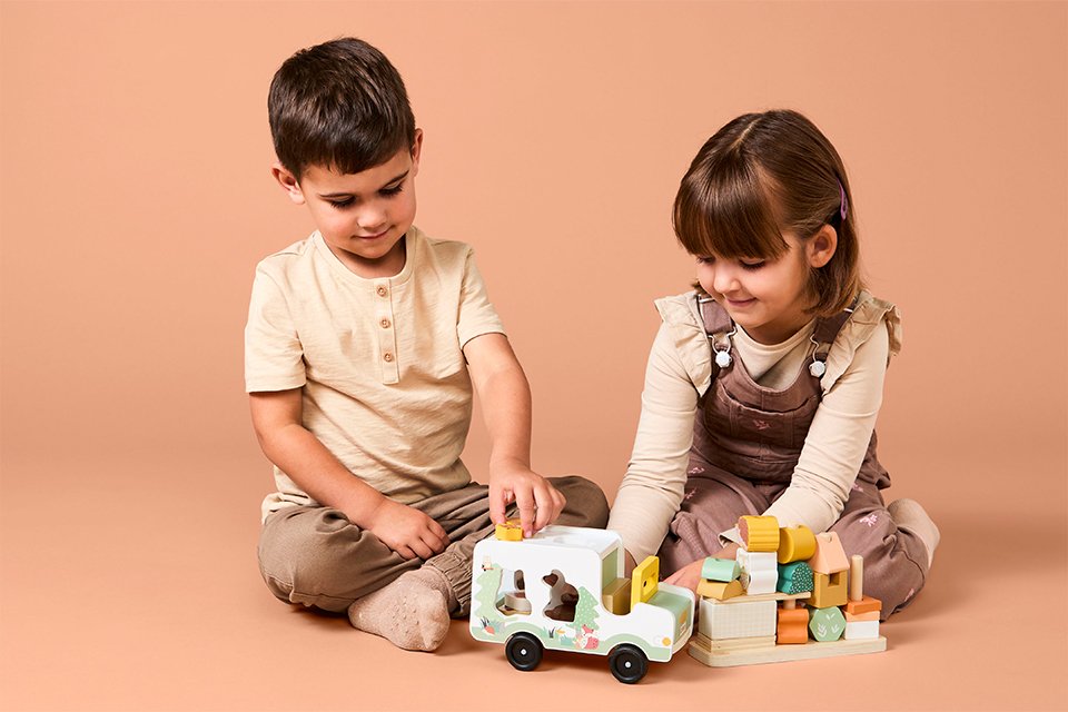 Two toodlers playing with a wooden Chad Valley toy car.