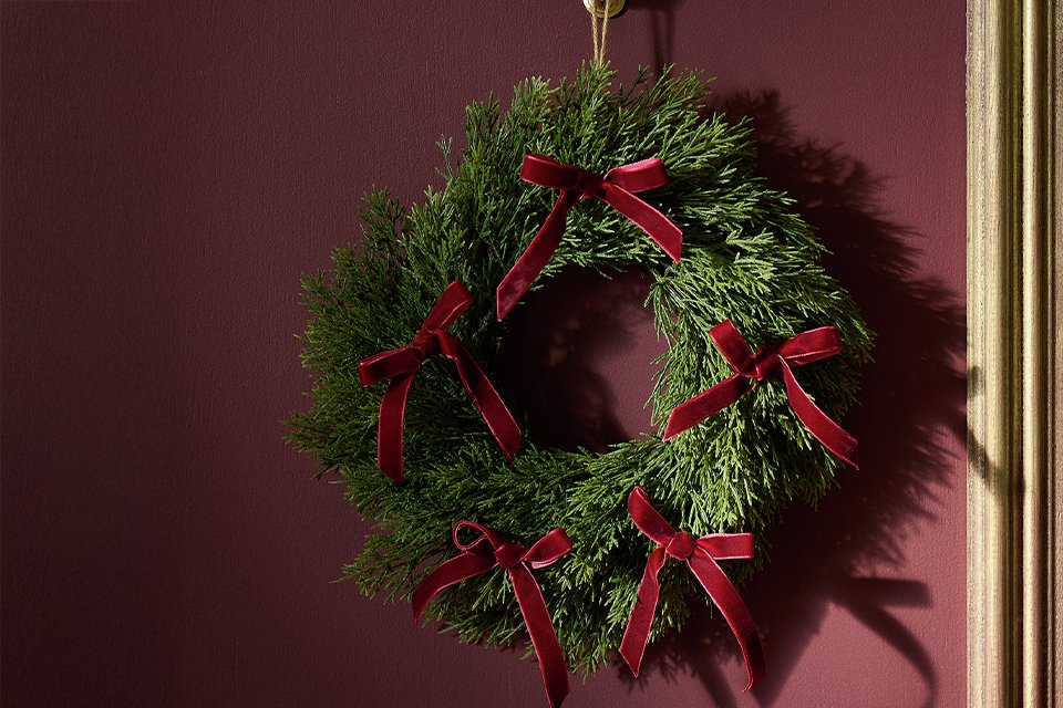 A wreath with red bows hung on a door.
