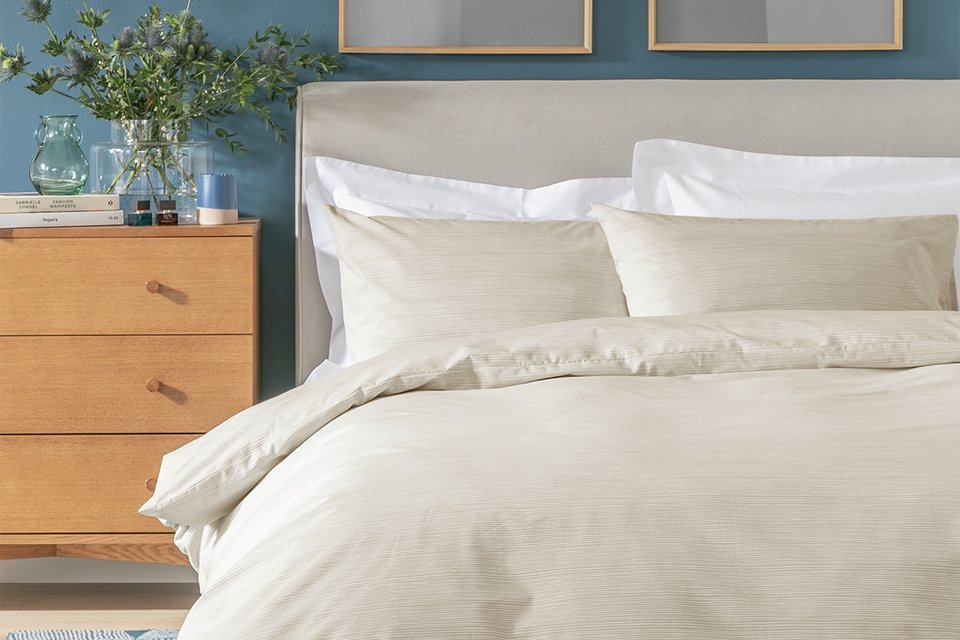 A bed made with a Habitat neutral bedding set.
