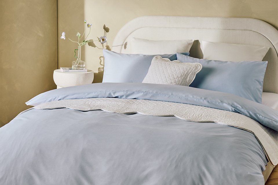A bed made with a Habitat pale blue bedding set and matching pillows.
