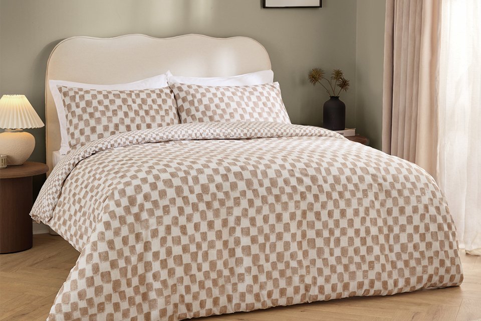 A bed made with a Hoem Nyhavn brown single bedding set.