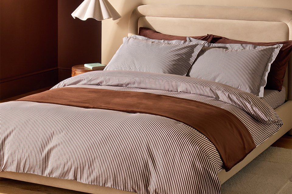 A bed made with a Habitat cotton Oxford edge super king size bedding set.