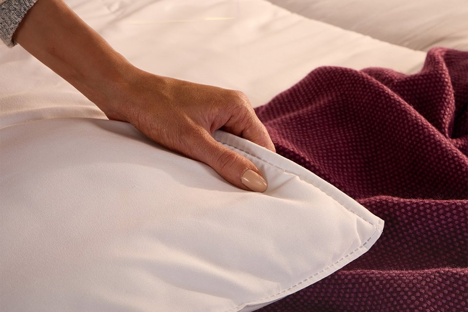A woman touching a cosy Slumberdown 10.5 tog duvet.