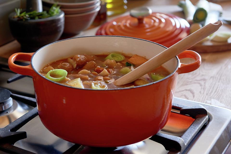 An image of an orange casserole pot with a stew in it.