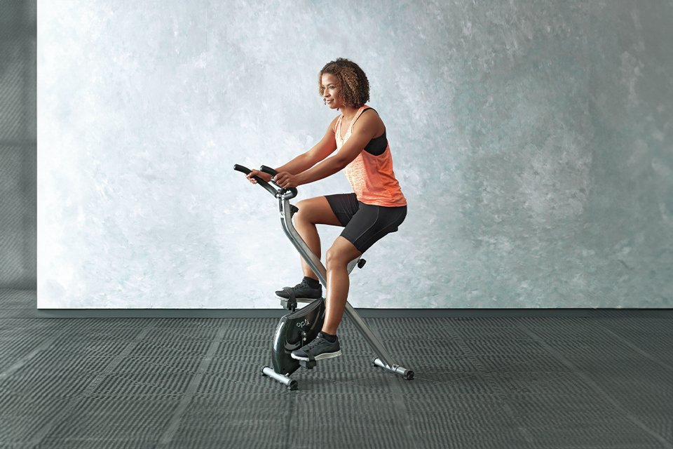 A woman exercising on Opti Folding Magnetic Exercise Bike.