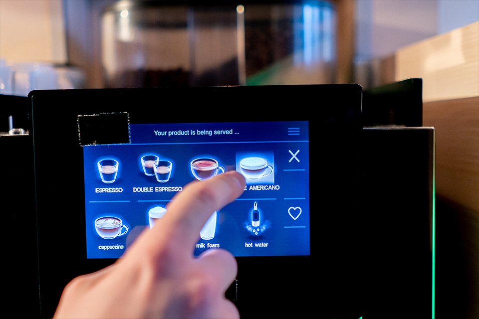 A person selecting a coffee using LED display on a coffee.