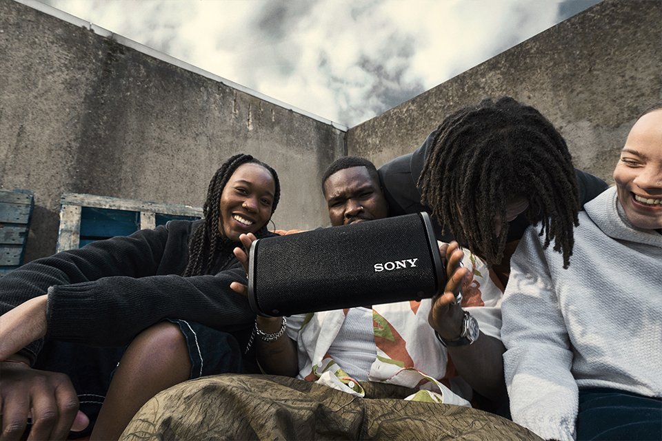 A group of friends sitting and listening to music via Sony Field speaker.