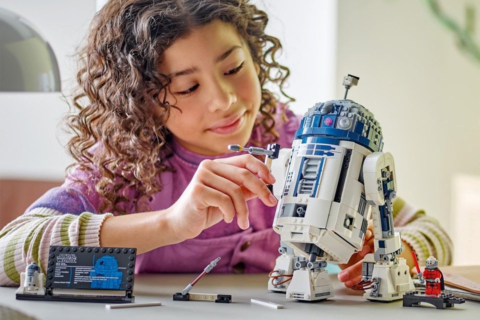 A young girl building LEGO Star Wars R2-D2 model, buildable toy droid figure 75379.