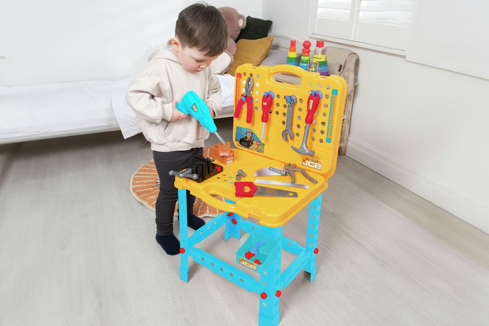 A boy playing with JCB my first workbench and tool.