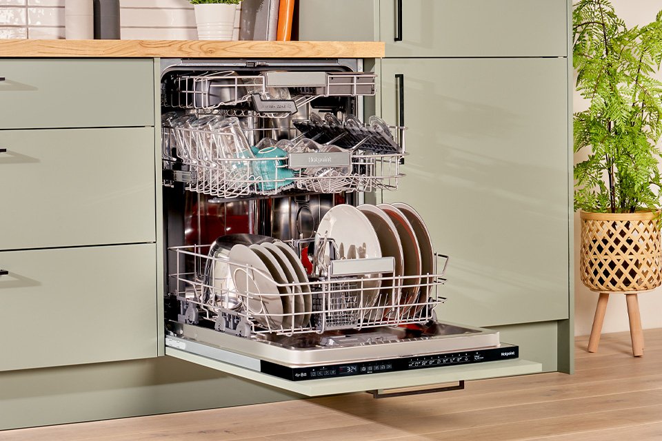 Hotpoint full size dishwasher seamlessly built into modern green kitchen cabinets.