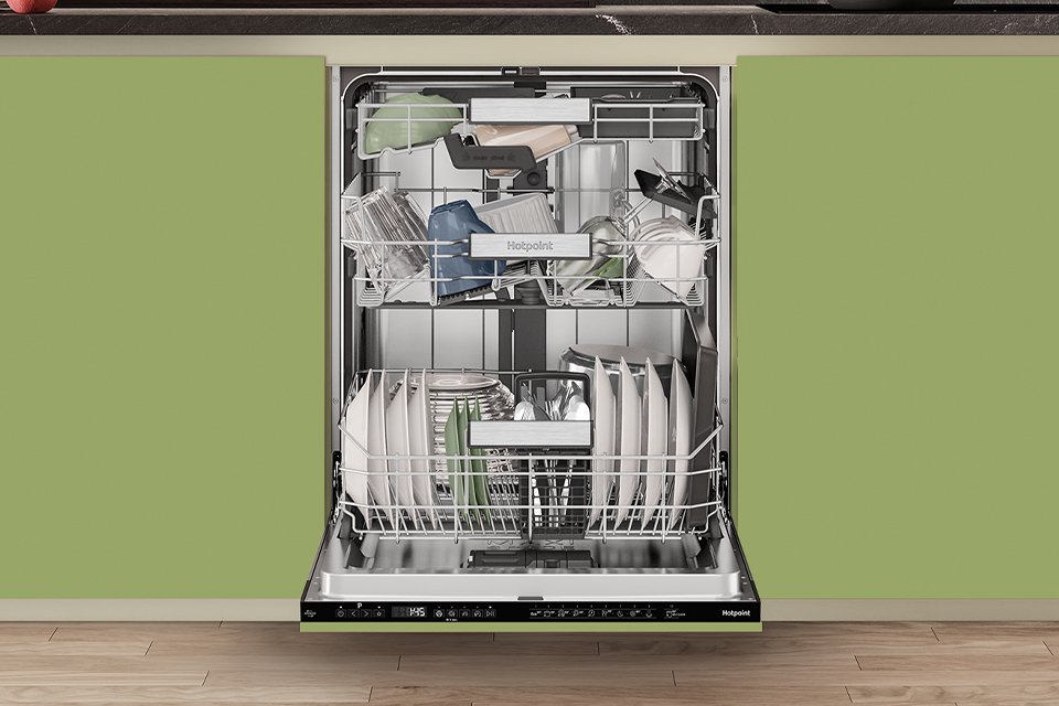 A Hotpoint full size dishwasher seamlessly built into modern green kitchen cabinets.