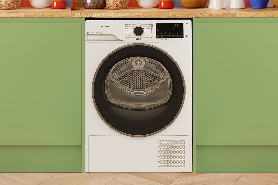 A Hotpoint white tumble dryer seamlessly built into modern green kitchen cabinets.