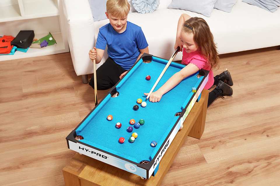 Siblings playing snooker pool at home.