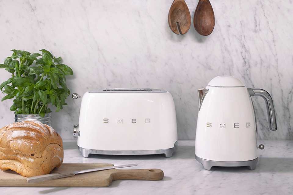 A white Smeg kettle and toaster placed on marble counter.