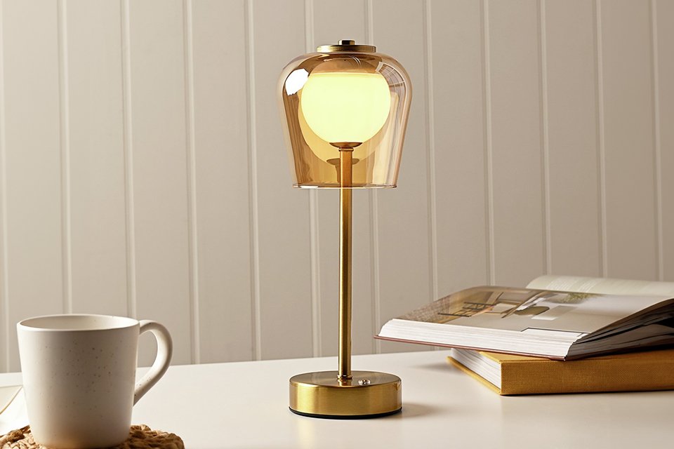 A Hestia LED rechargeable touch table lamp in bronze finish placed on a table.