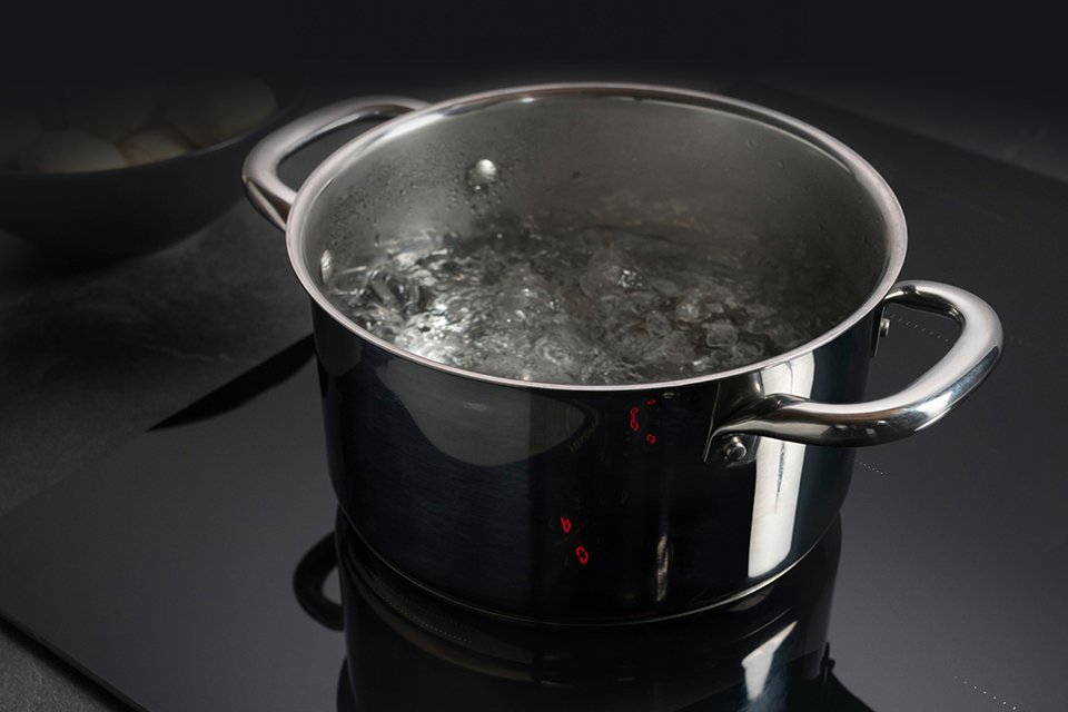 A pot of boiling water on a hob.