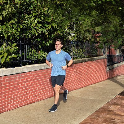 A man wearing a black Garmin Forerunner 55 GPS Running Smart Watch while running.