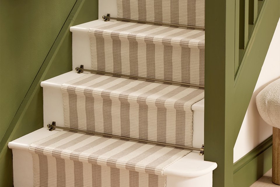 Habitat antique brass stair rods placed over a stair runner on some stairs.