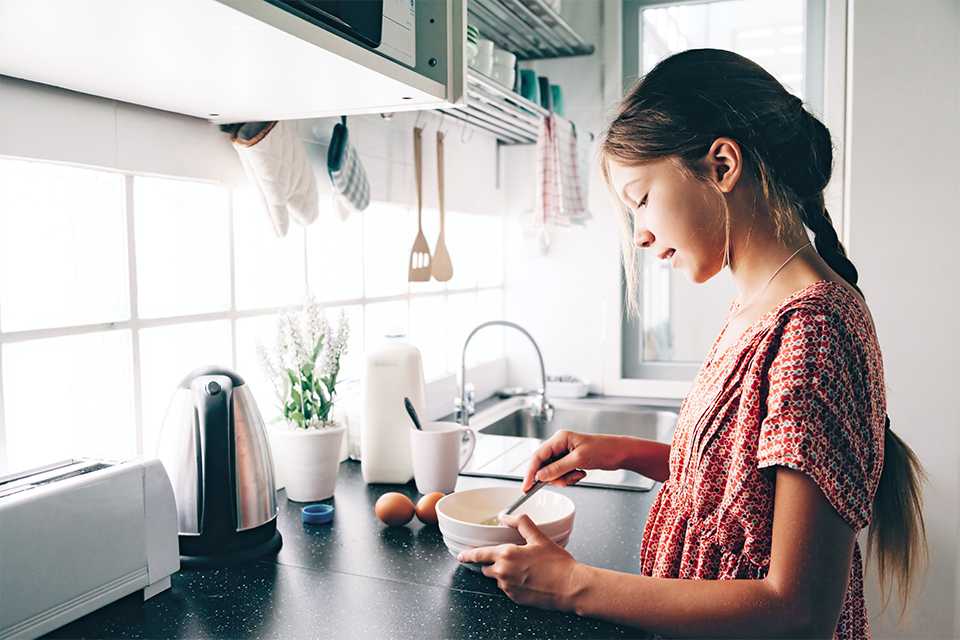 A girl using a mixing bowl in a kitchen.